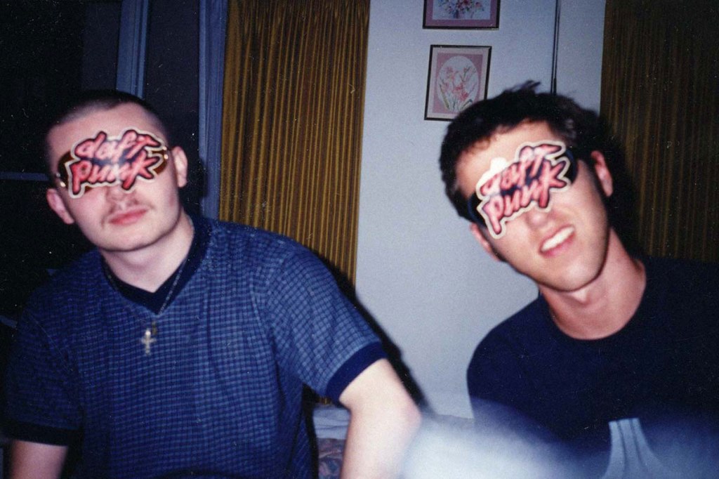 Both members of Daft Punk sitting next to each other with Daft Punk logos covering sunglasses over their eyes.