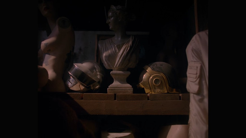 Daft Punk's helmets placed on a shelf among marble statues in what appears to be a museum's archives. The helmets have collected dust over time.