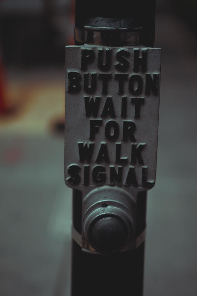 Crossing signal button with the message "Push button wait for walk signal"